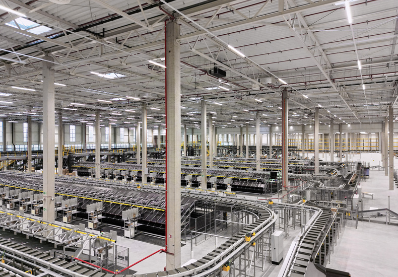 Automatisiertes Logistikzentrum mit Fördertechnik und Intralogistiksystemen. Die moderne Lagerhalle ermöglicht einen effizienten Materialfluss sowie leistungsstarke Lager- und Versandprozesse.