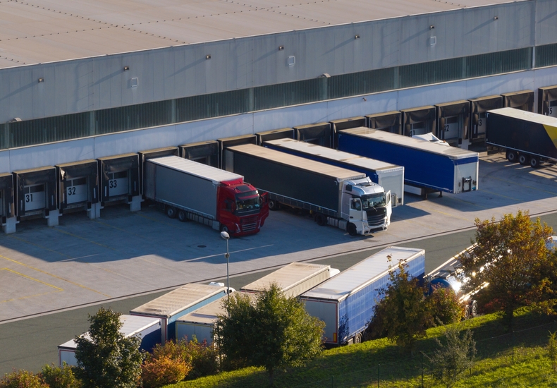 Lkw an Laderampen eines Logistikzentrums für den Einkauf von Logistikdienstleistungen Logistikzentrum mit mehreren Lkw an den Laderampen als Symbol für Transport-, Lager- und Logistikdienstleistungen im strategischen Einkauf.