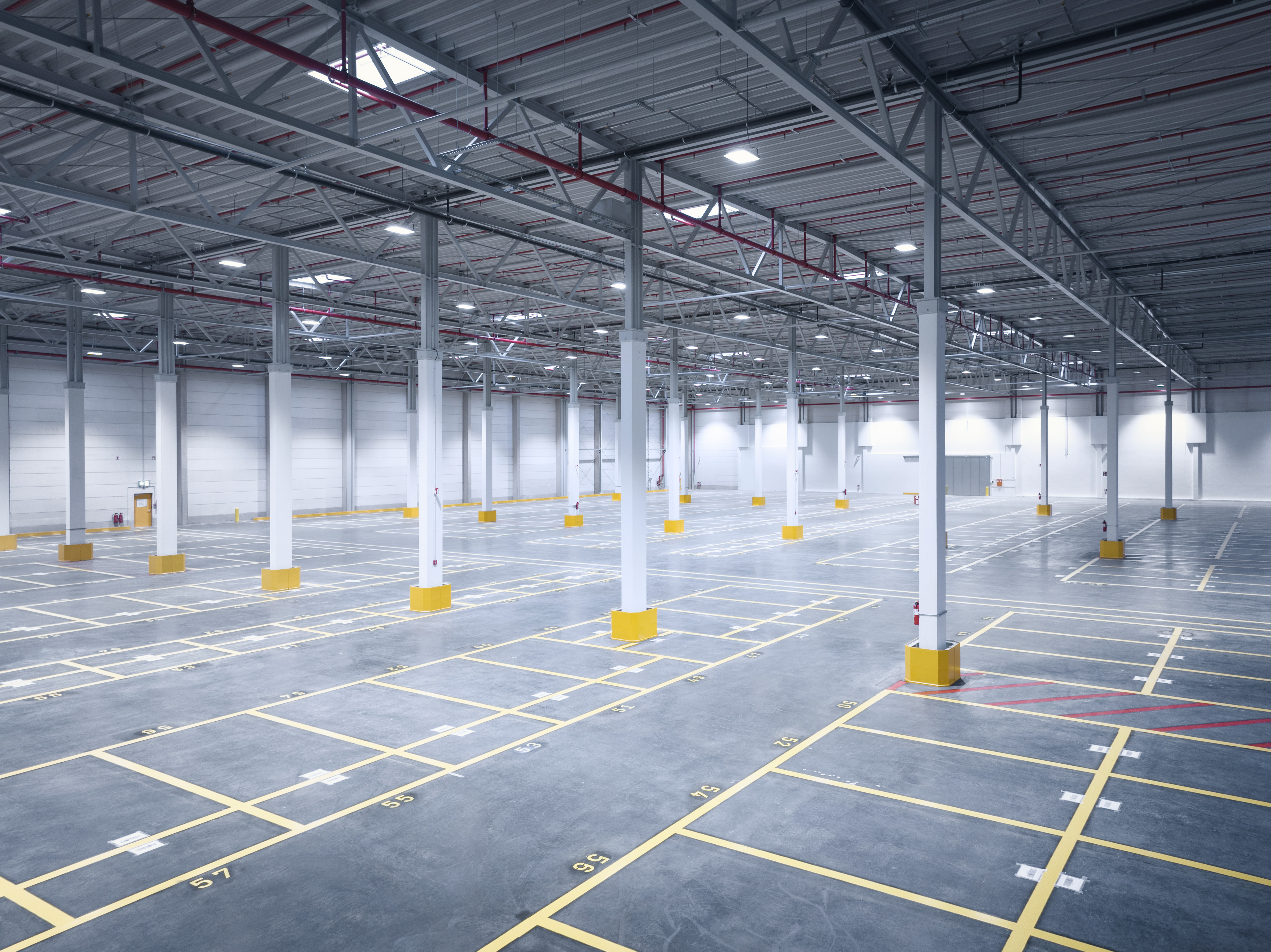 Leere Industriehalle mit markierten Flächen, symbolisiert Planung und Umsetzung im Industriebau.